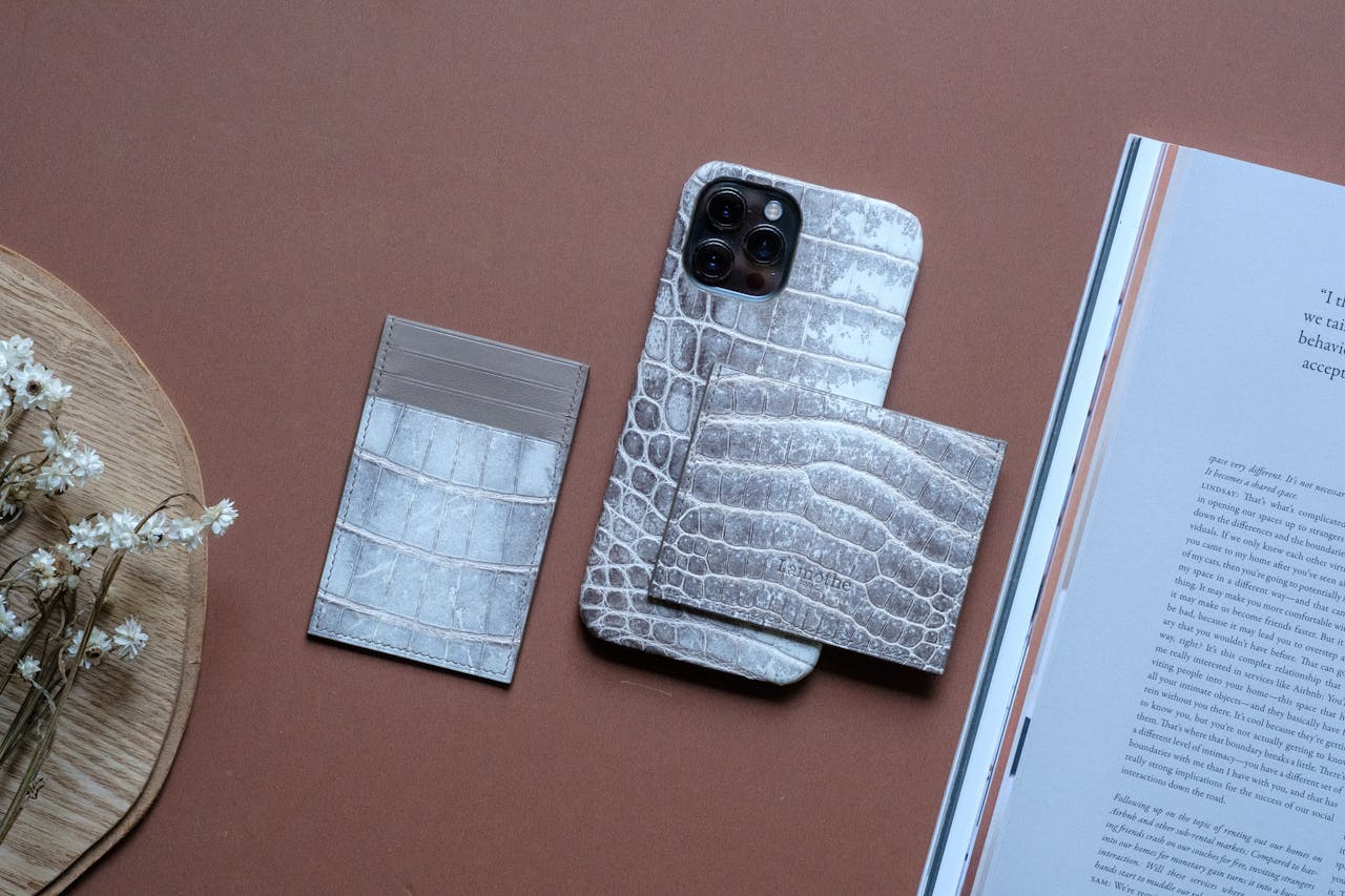 Flat lay image showcasing crocodile leather accessories including smartphone case and wallet.